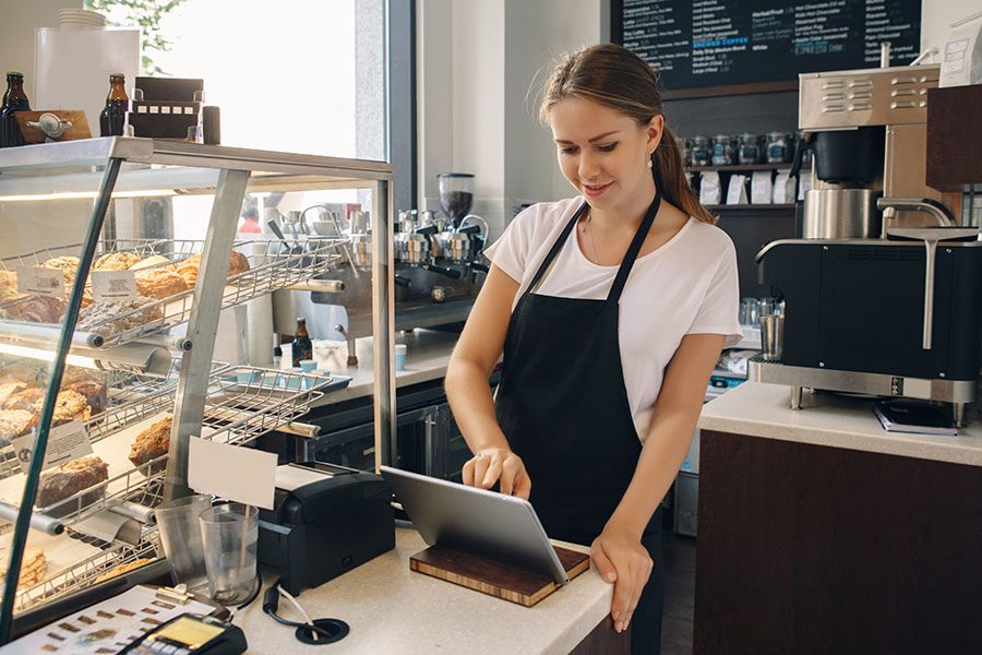 Business Insurance - Portrait of a Small Business Coffee Shop Owner Using a Tablet to Process Payments